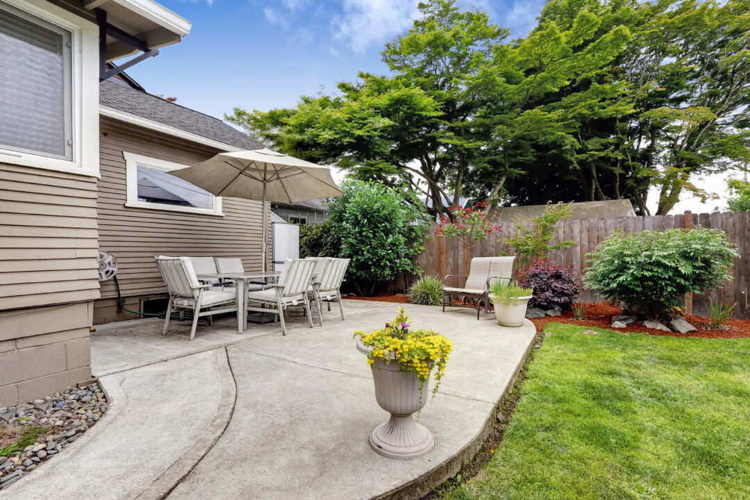 Backyard patio area with table set and umbrella. Patio with concrete floor and flower pots in Tulsa Oklahoma